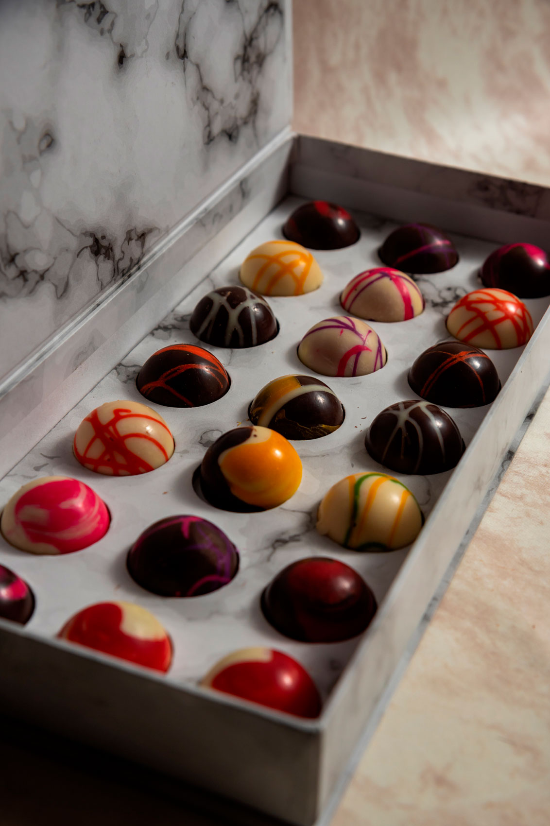 Caja blanca de 21 Chocolates con Mensajes Relleno Frutal y Cacao 100% Mexicano sobre fondo de marmol para regalo empresarial