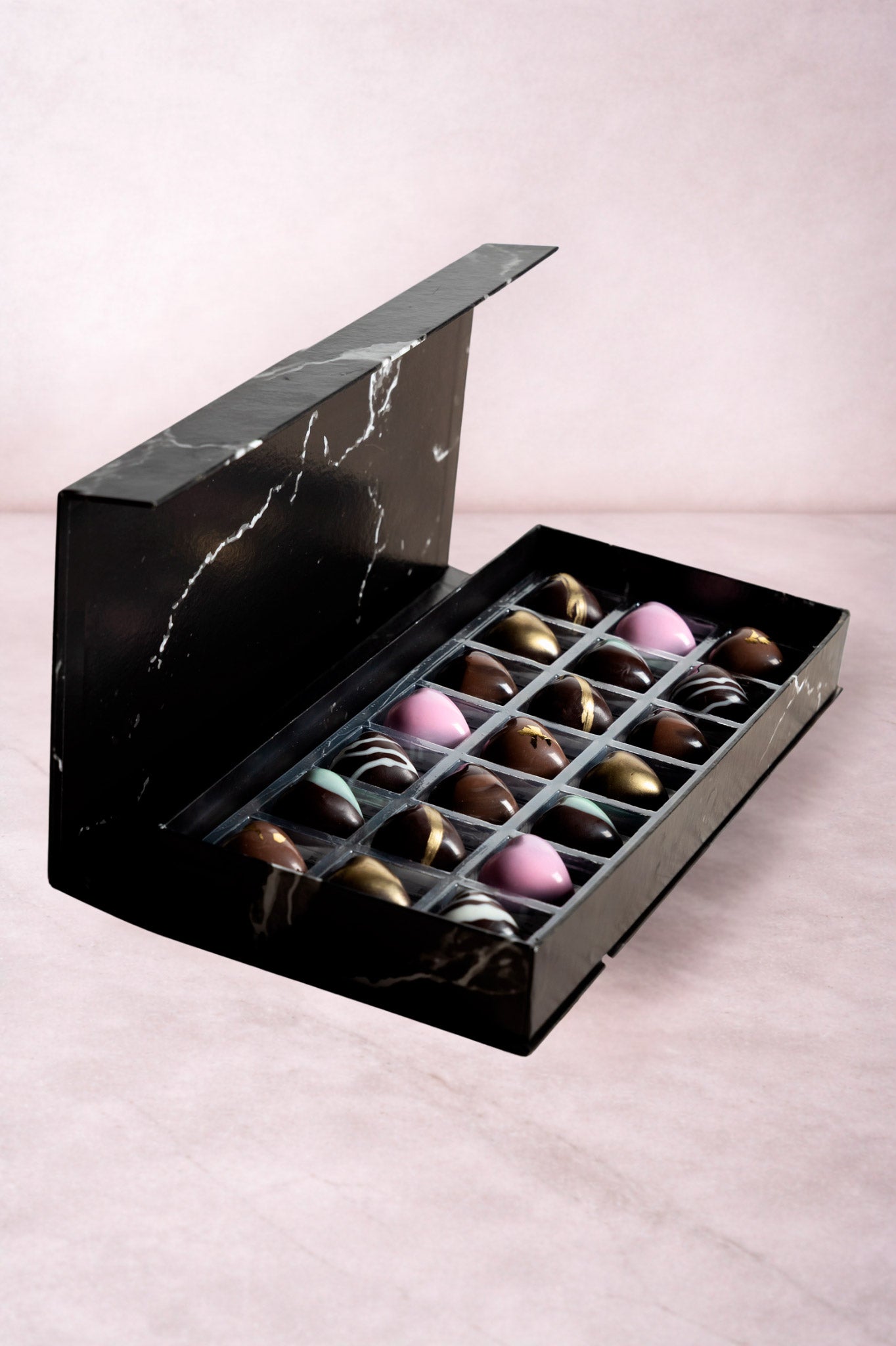 Caja de chocolates negros abiertos de la marca ChocoRoux con 21 piezas rellenas y diseño premium sobre fondo mármol.