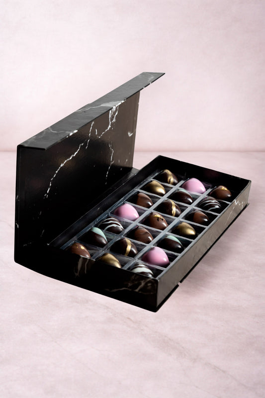 Caja de chocolates negros abiertos de la marca ChocoRoux con 21 piezas rellenas y diseño premium sobre fondo mármol.