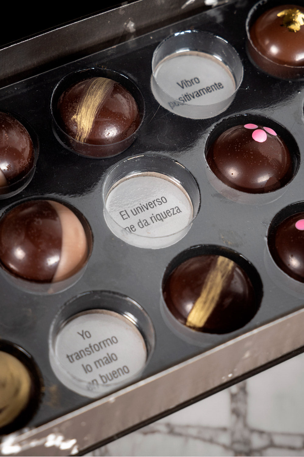 Caja de chocolates negros abiertos de la marca ChocoRoux con 21 piezas rellenas y diseño premium sobre fondo mármol.