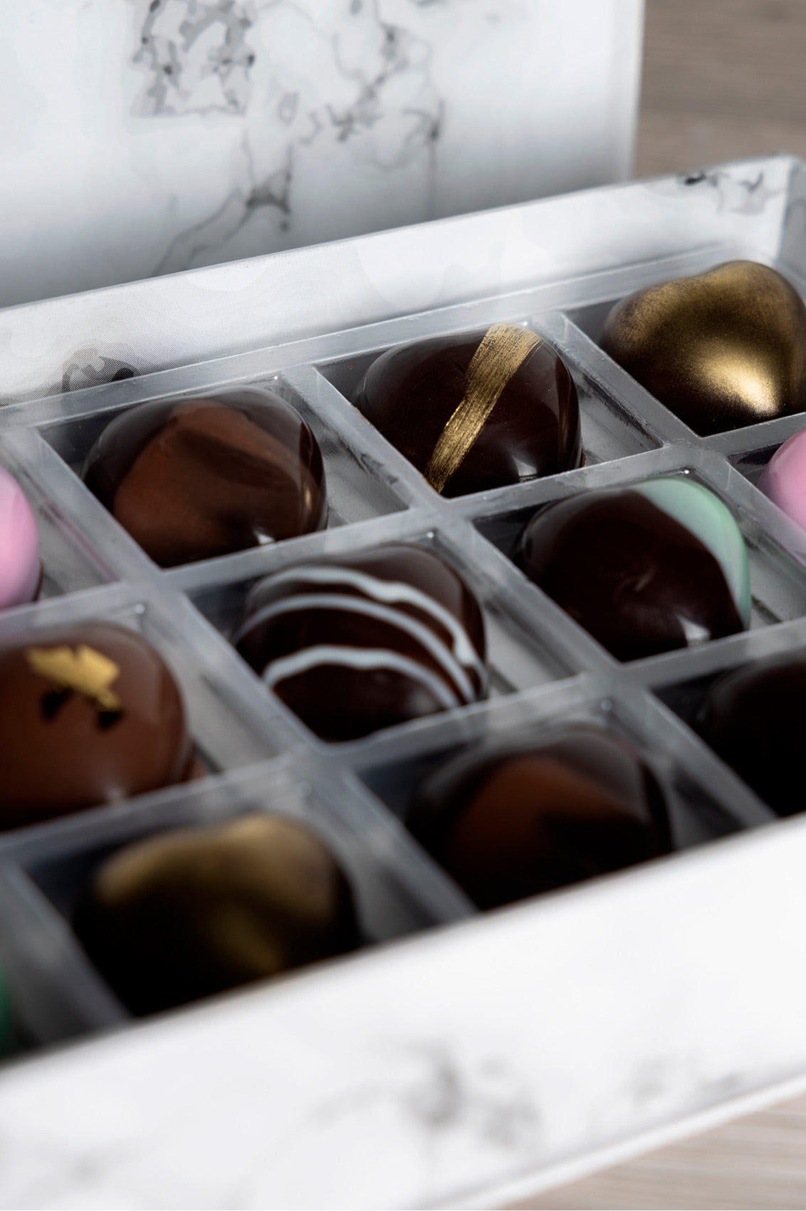 Caja blanca de chocolates negros abiertos de la marca ChocoRoux con 21 piezas rellenas y diseño premium sobre fondo mármol.