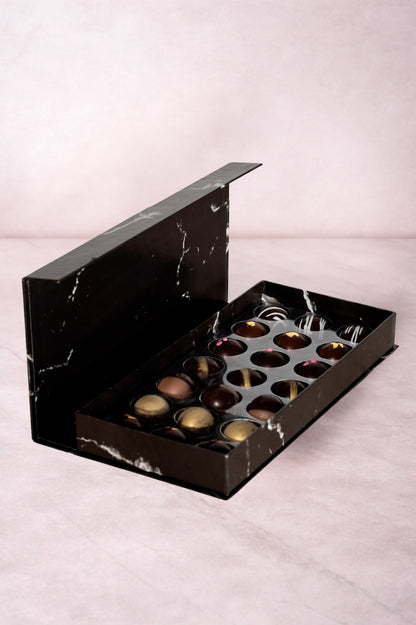 Caja de chocolates negros abiertos de la marca ChocoRoux con 21 piezas rellenas y diseño premium sobre fondo mármol.