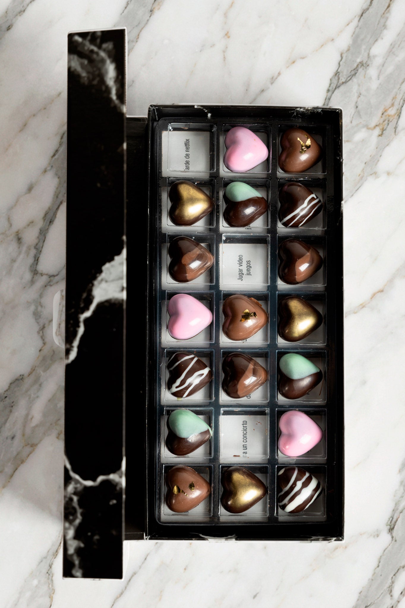 Caja de chocolates negros abiertos de la marca ChocoRoux con 21 piezas rellenas y diseño premium sobre fondo mármol.