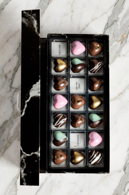 Caja de chocolates negros abiertos de la marca ChocoRoux con 21 piezas rellenas y diseño premium sobre fondo mármol.