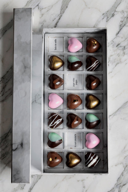 Caja blanca de chocolates negros abiertos de la marca ChocoRoux con 21 piezas rellenas y diseño premium sobre fondo mármol.