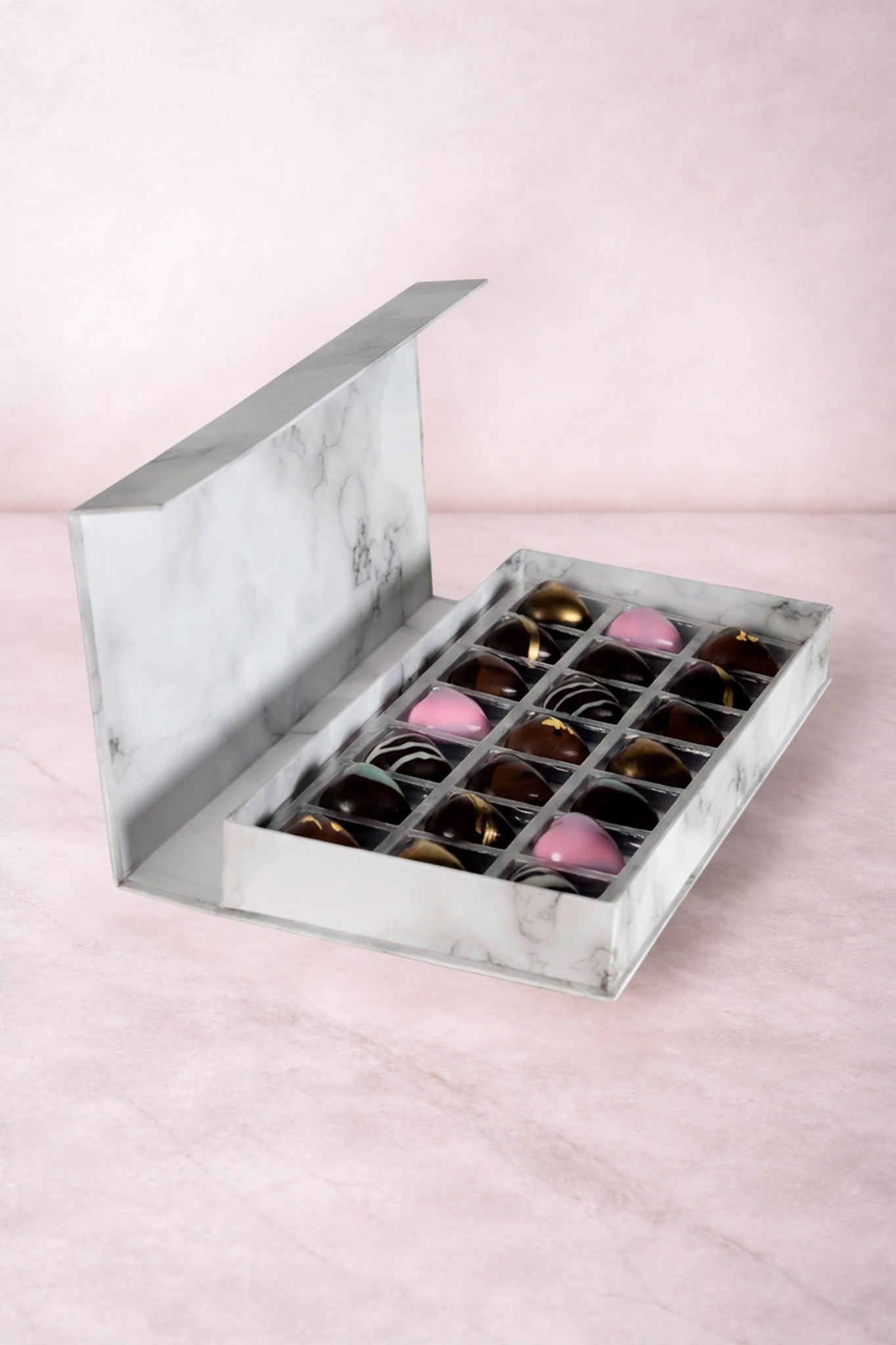 Caja blanca de chocolates negros abiertos de la marca ChocoRoux con 21 piezas rellenas y diseño premium sobre fondo mármol.