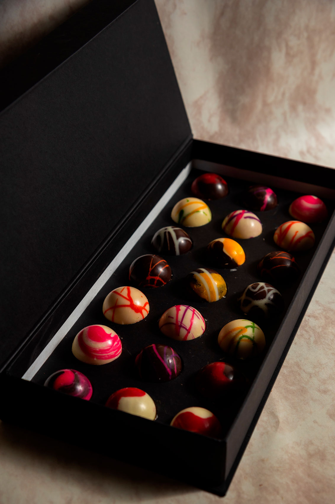 Caja Negra de 21 Chocolates con Mensajes Relleno Frutal y Cacao 100% Mexicano Fondo de Marmol