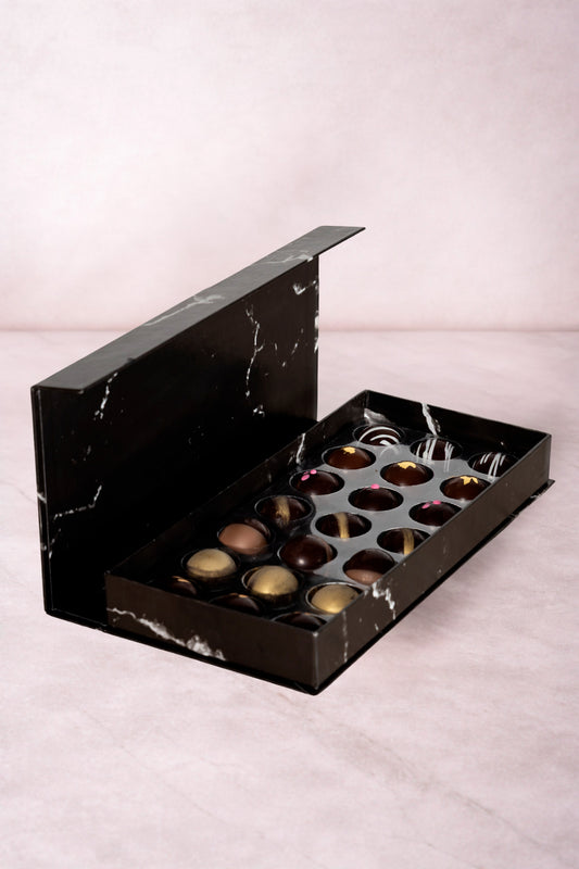 Caja de chocolates negros abiertos de la marca ChocoRoux con 21 piezas rellenas y diseño premium sobre fondo mármol.